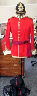 An Edwardian Blue Cloth Helmet, Tunic with waist sash, Trousers, and pattern Wellington boots to an Officer in The Northamptonshire Regiment.