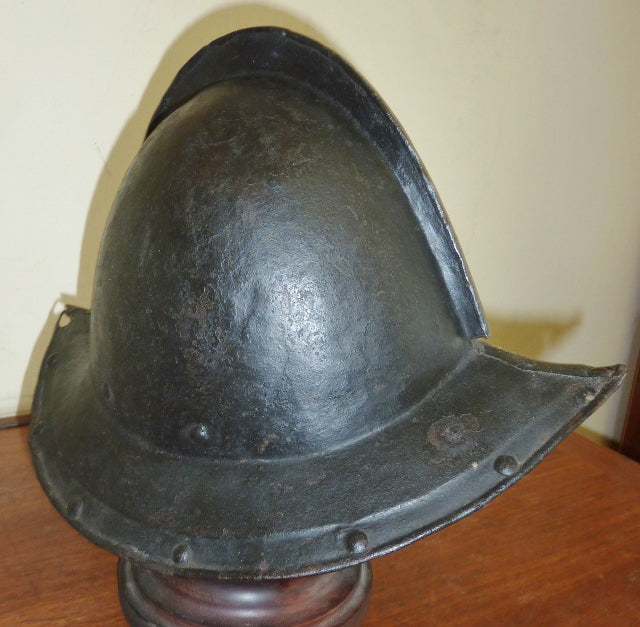 A English PIKEMANS POT circa 1650 formed in two halves joined by a turn over low comb. Broad down turned brim with all rivets present. Display holes to both ends of the points. Black tar type paint.
